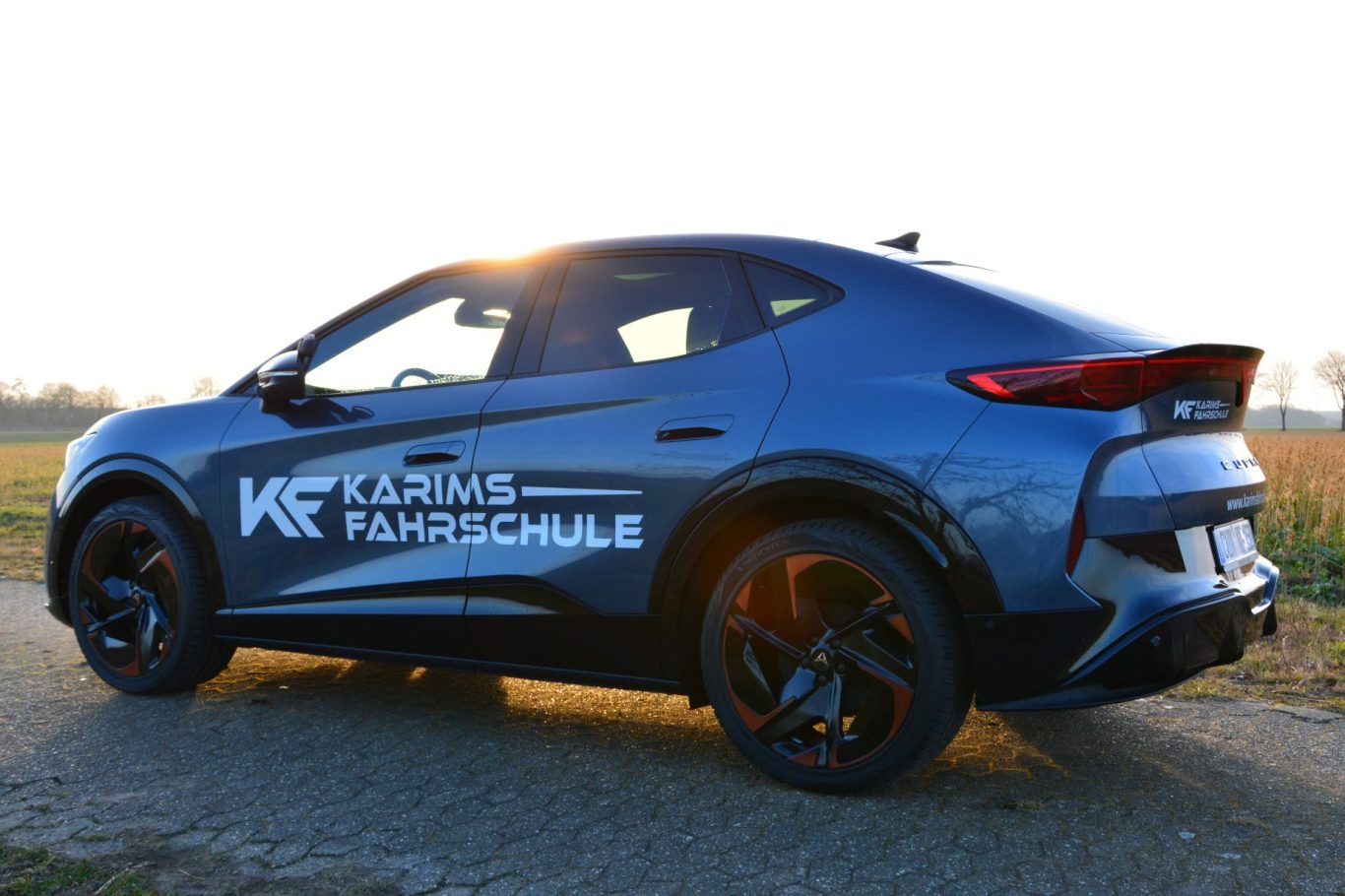 Dunkelblauer SUV mit auffälliger Seitenbeschriftung auf einer Landstraße.
